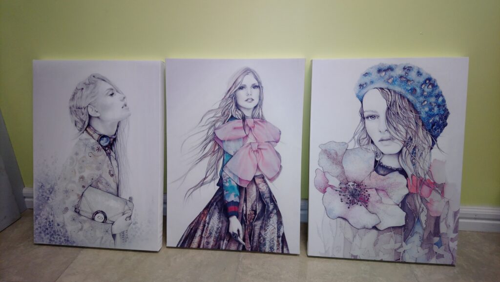 A series of fashion illustrations on canvas, leaning against a wall