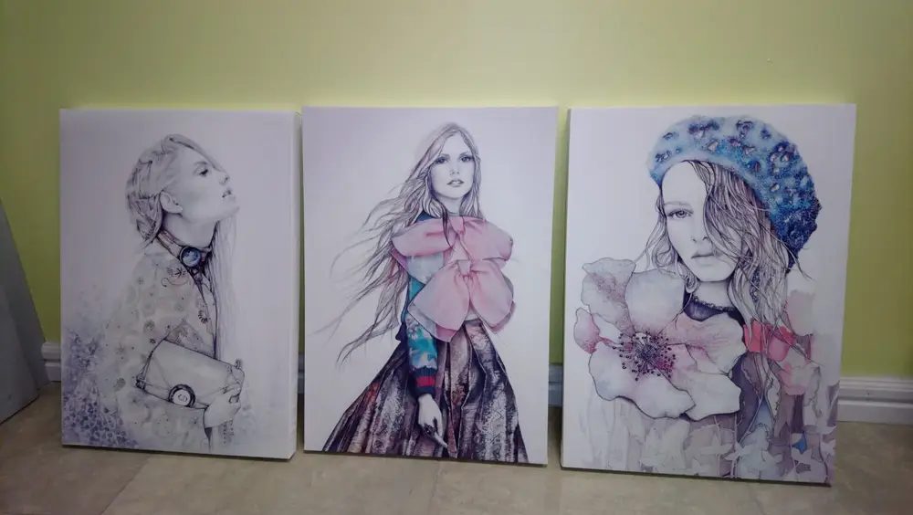 Three drawings of female figures printed on canvas, propped against a wall