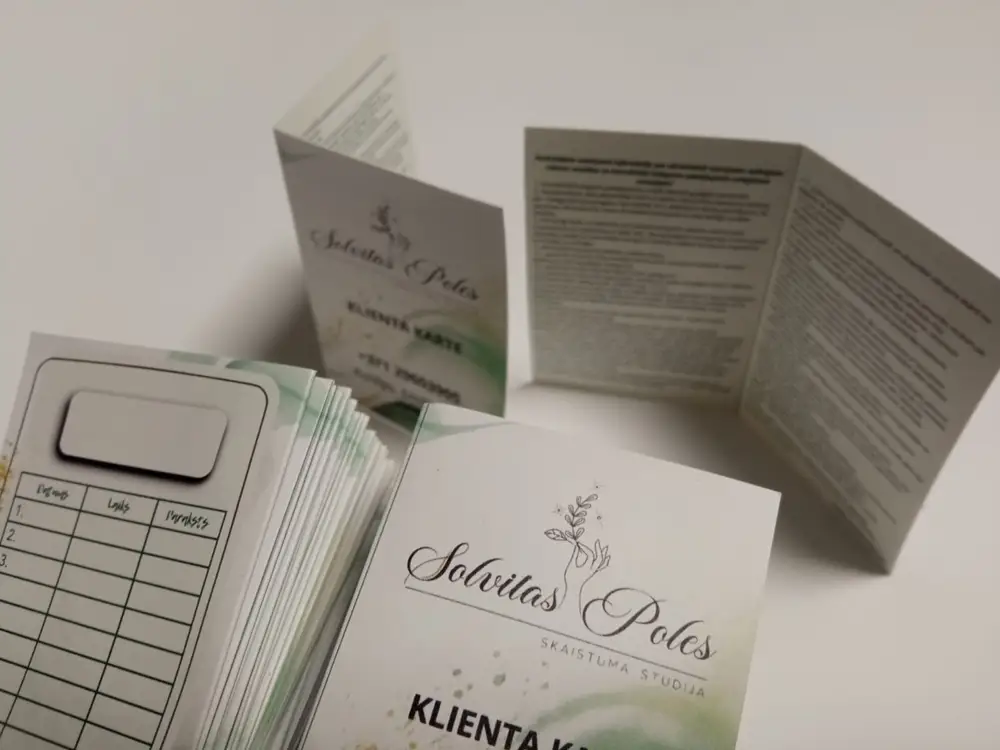 A stack of client cards and folded cards reading Solvitas Poles skaistuma studija