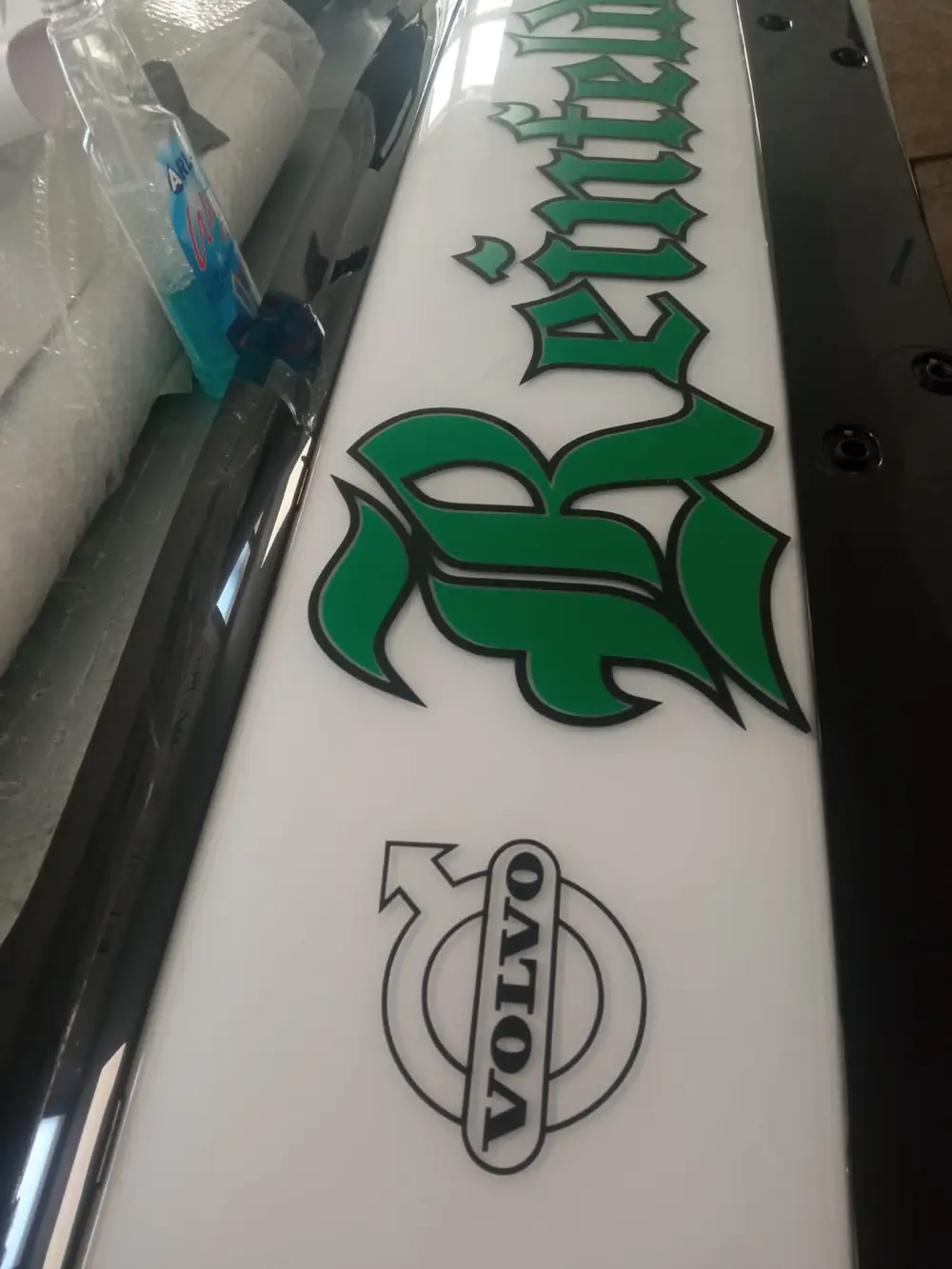 White panel with green Gothic-style lettering and a Volvo logo on a truck