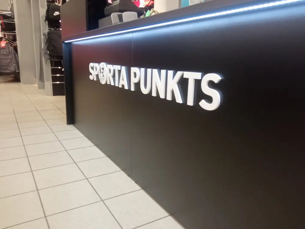 Black shop counter with white 3D letters reading Sporta Punkts