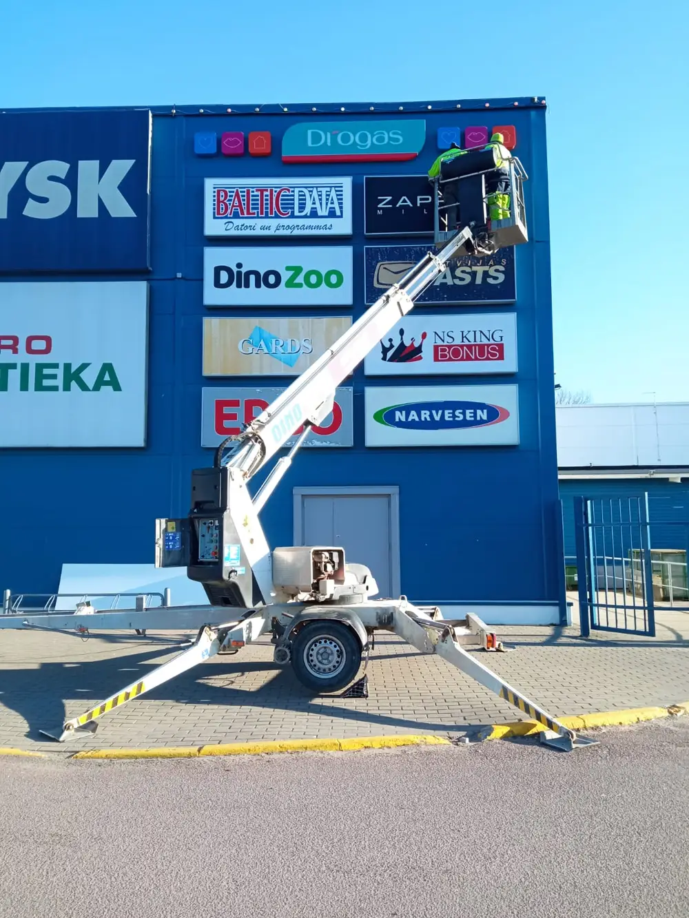 Blue shop facade with a sign board and a lift during installation