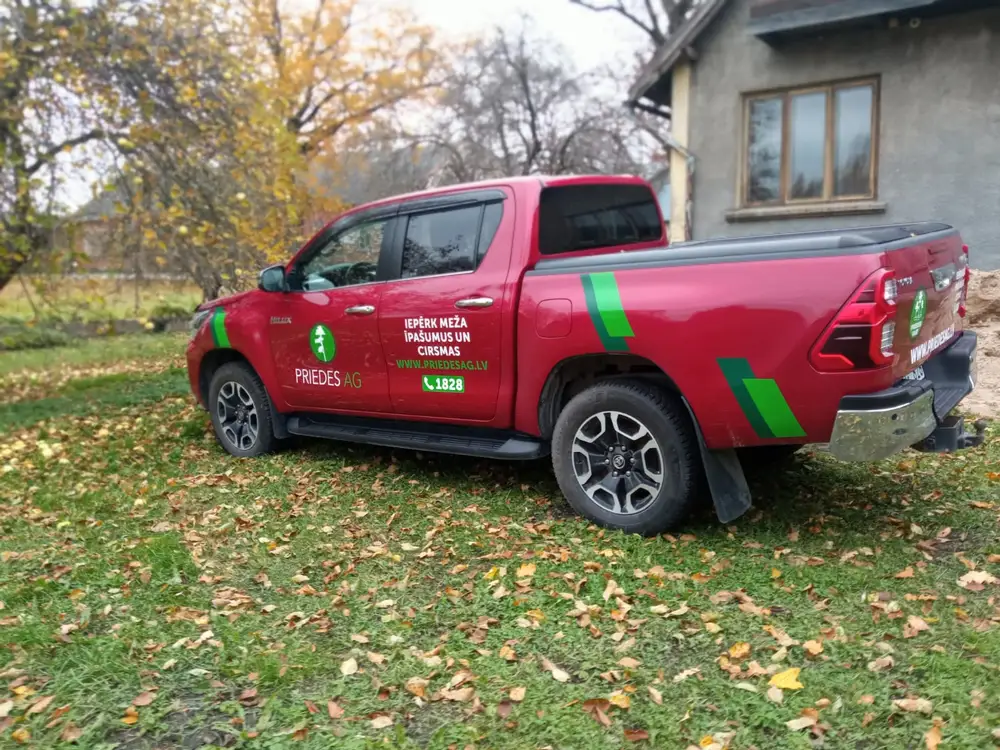 Red pickup truck with Priedes AG lettering and green side stripes