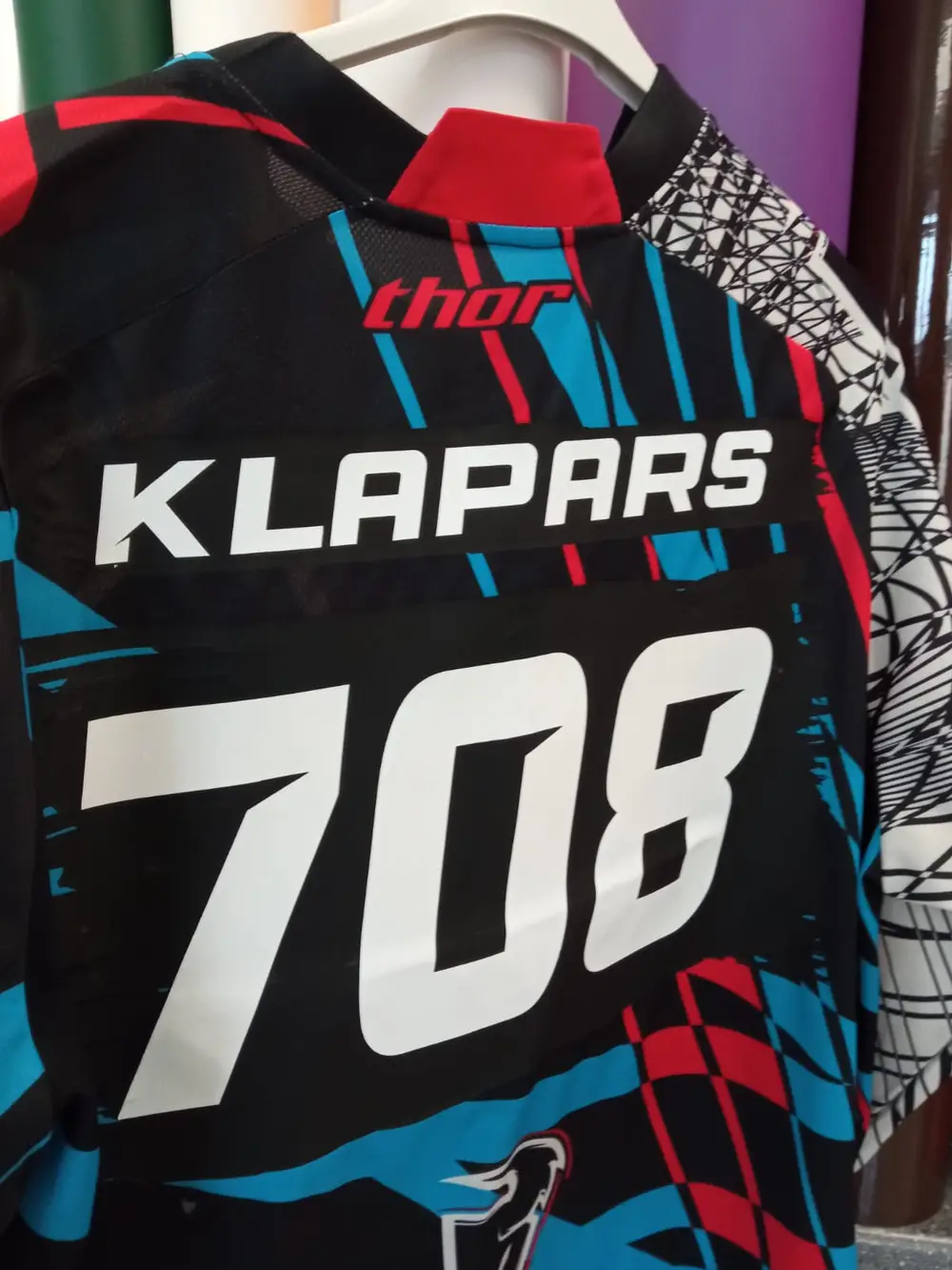 Colourful motocross jersey with a white surname and the number 708 on the back