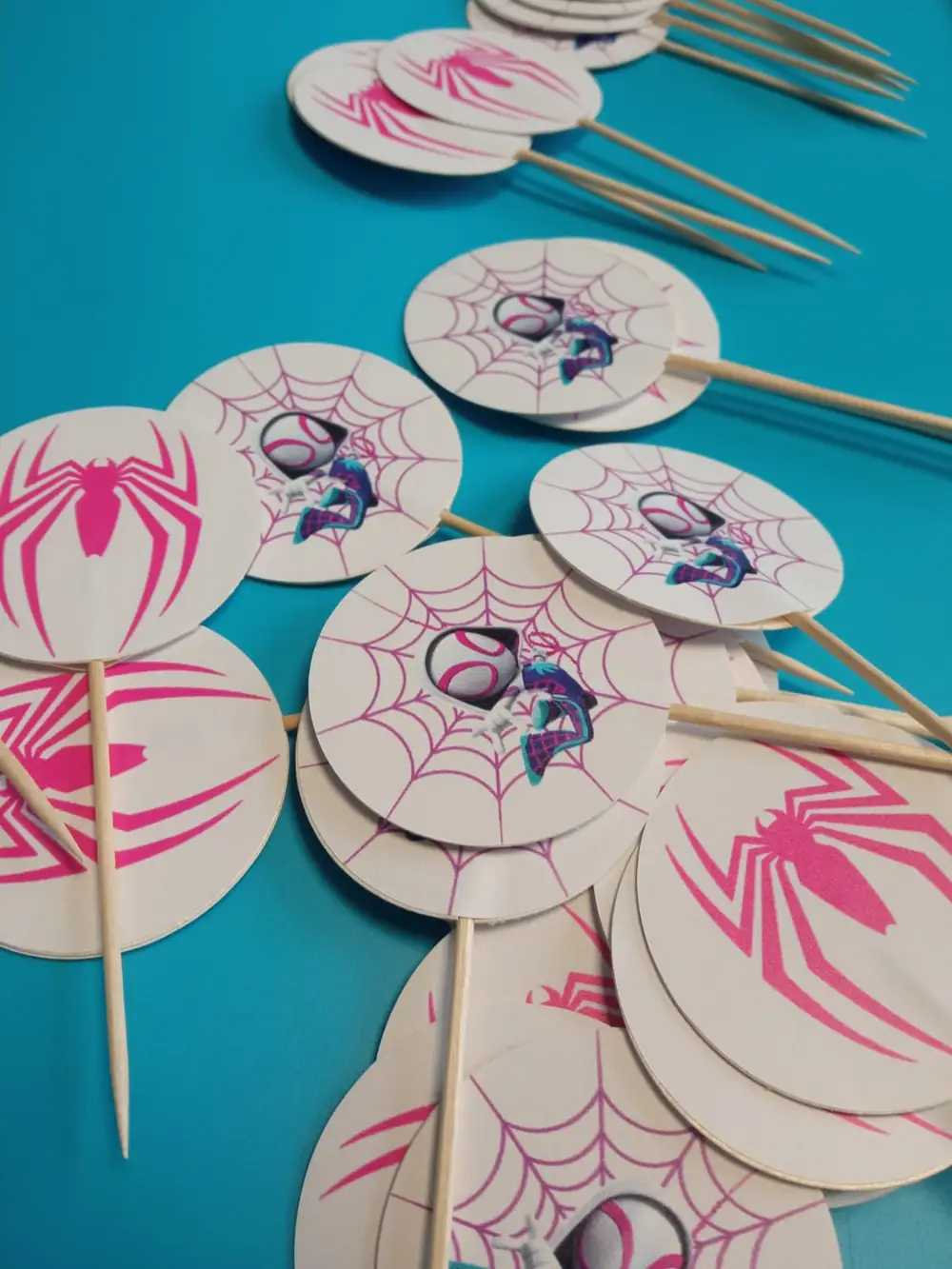 Round cardboard toppers with a pink spider motif on wooden sticks