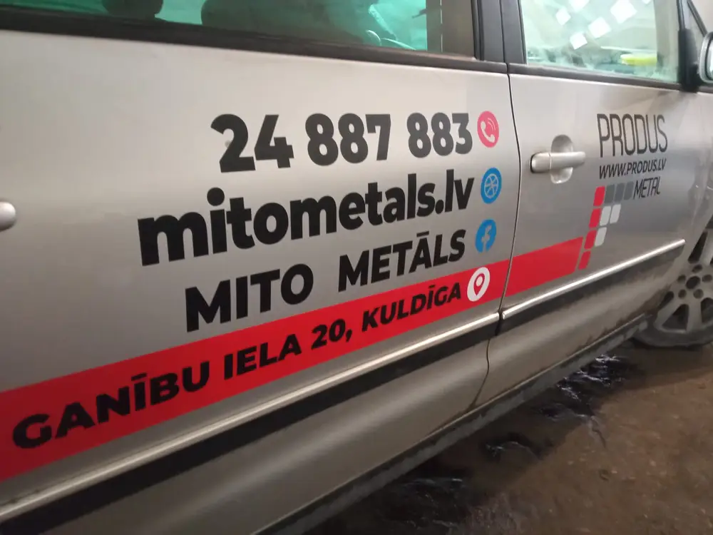 Other side of the silver car with Mito Metāls, Produs and a phone number
