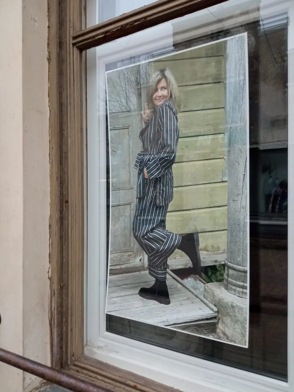 Shop window poster of a woman in a striped suit by a wooden wall